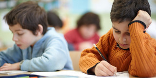 Tschau Im Klassenraum: Zwei Kinder bearbeiten ihre Schulaufgaben